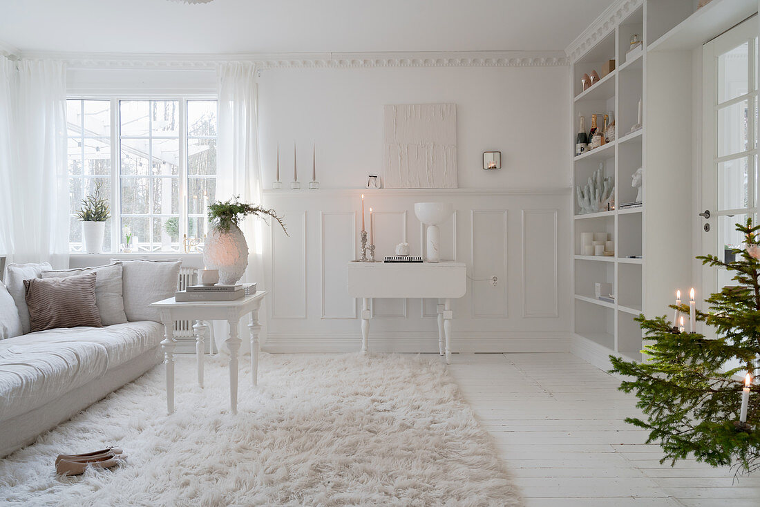 Wohnzimmer ganz in Weiß mit Kassettenwand und Winterdeko