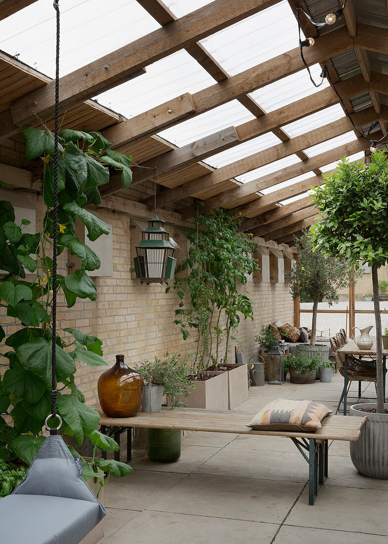 Beer-garden benches used as partition in conservatory with brick walls