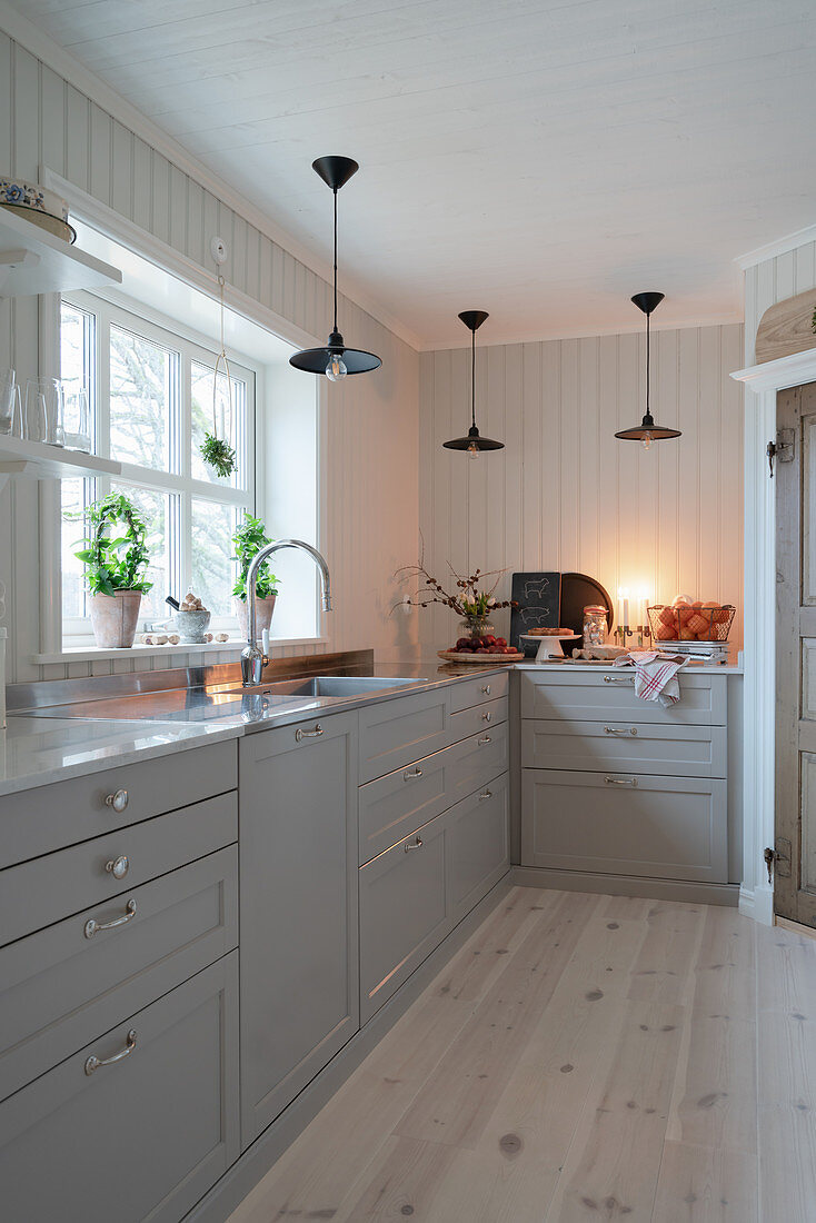 Scandinavian country-house kitchen decorated in white and grey with wood-clad walls