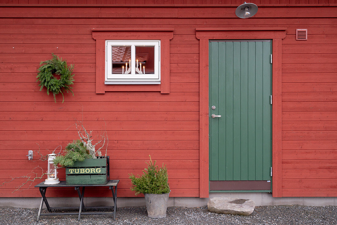 Grüne Holztür im roten Schwedenhaus mit schlichter Winterdeko