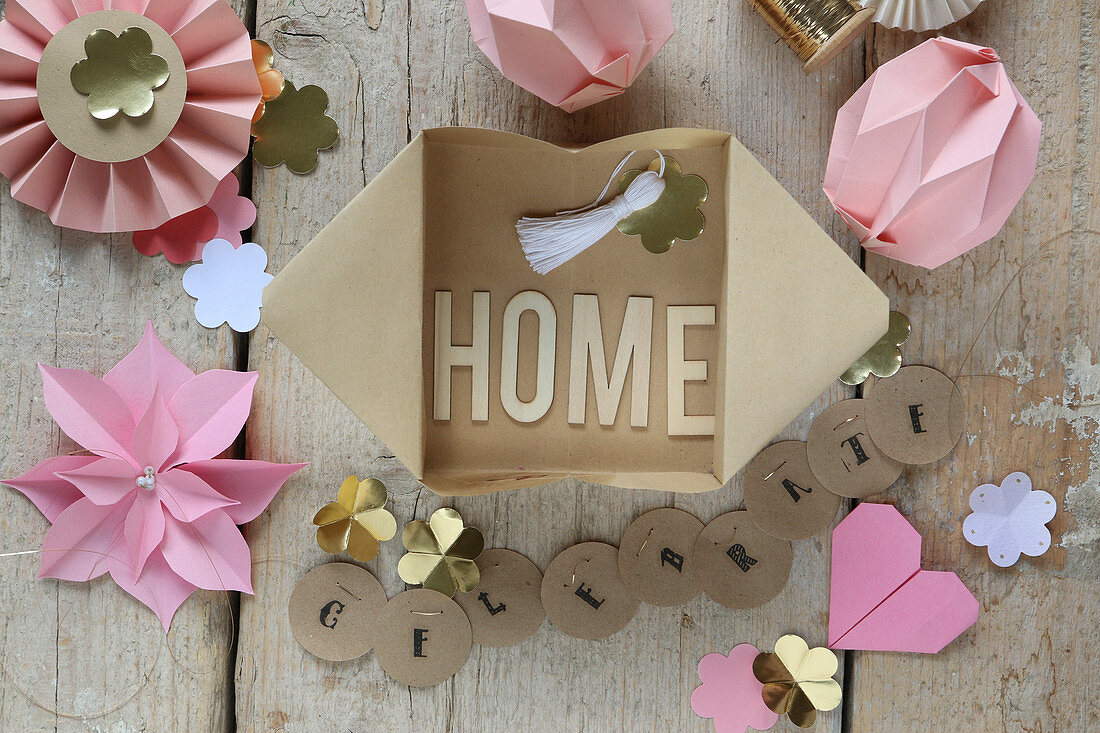 The word 'Home' made from letters in paper box surrounded by handmade paper decorations