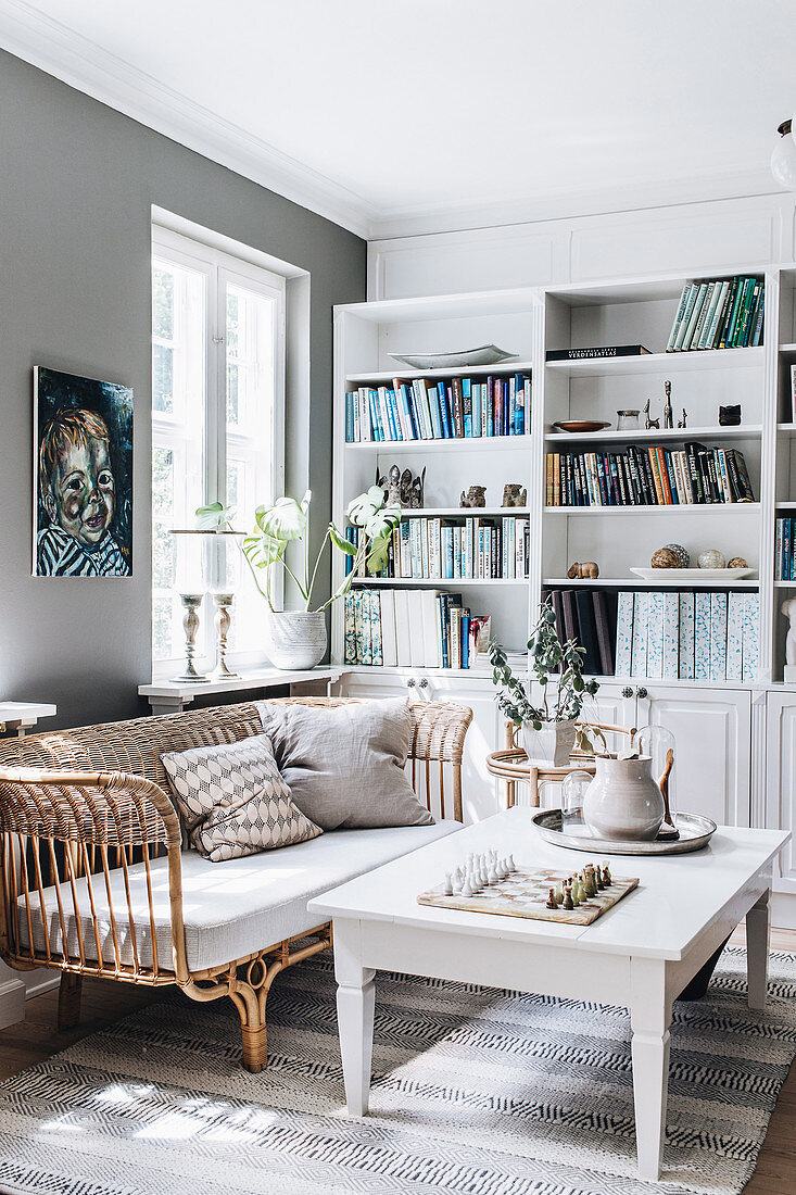 White table, rattan sofa and shelf wall in the living room