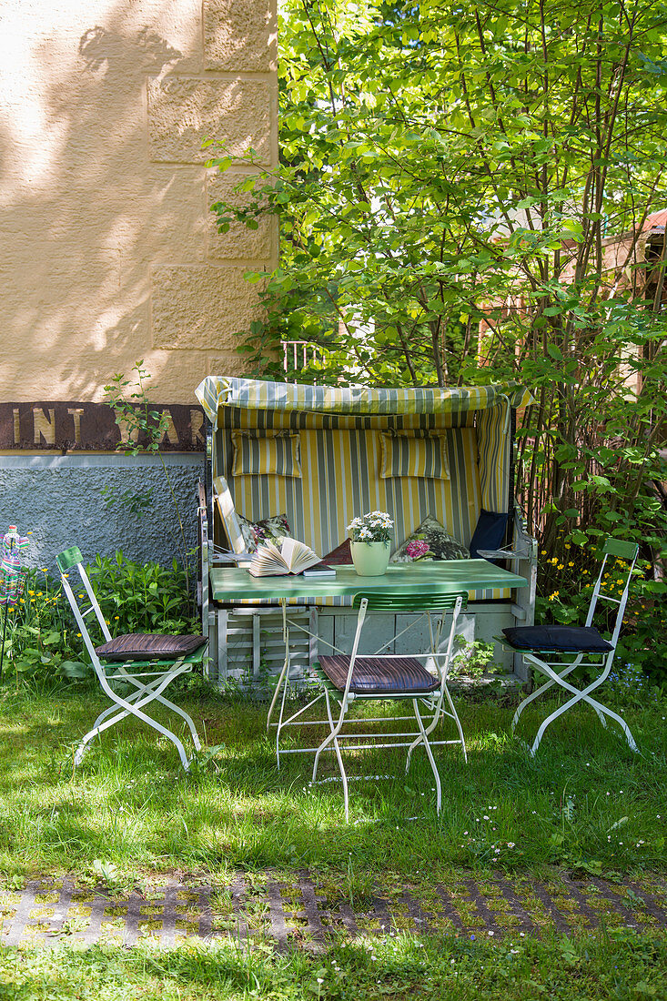 Garden table and beach chair in summery garden behind house