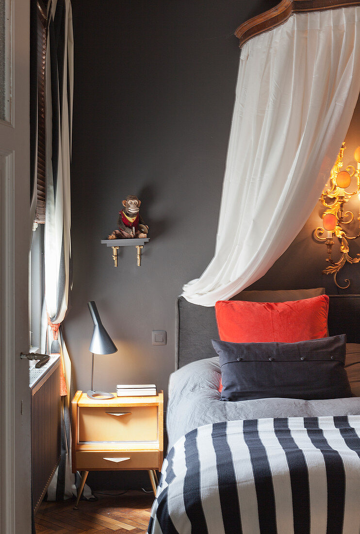 Bed with canopy in bedroom with dark grey wall