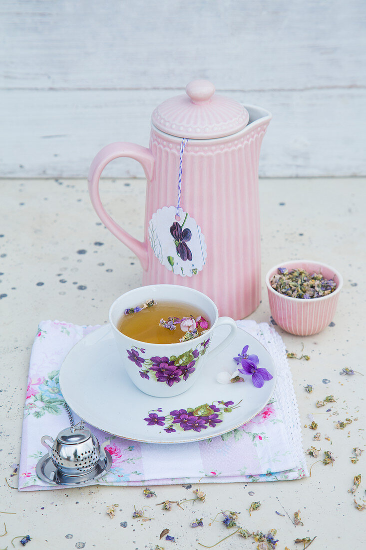 Violet infusion in floral teacup and insulated teapot