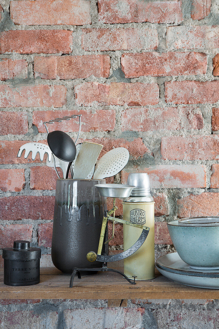 Kitchen utensils on shelf on rustic brick wall
