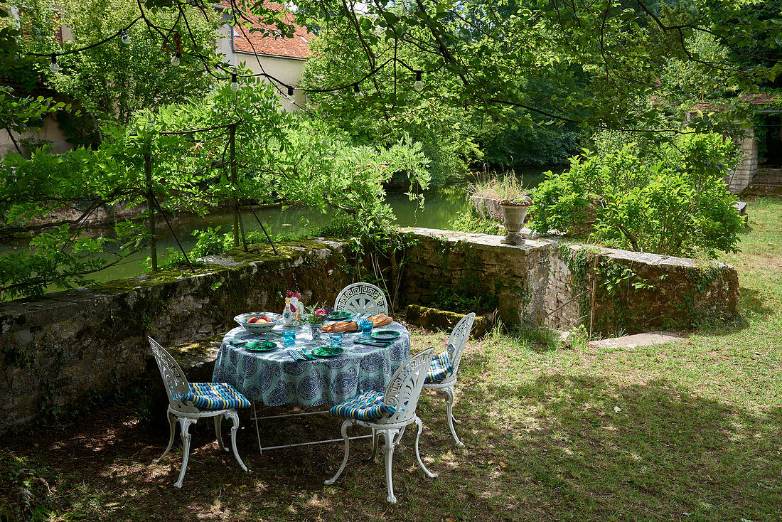Circular table and chairs in garden on riverbank
