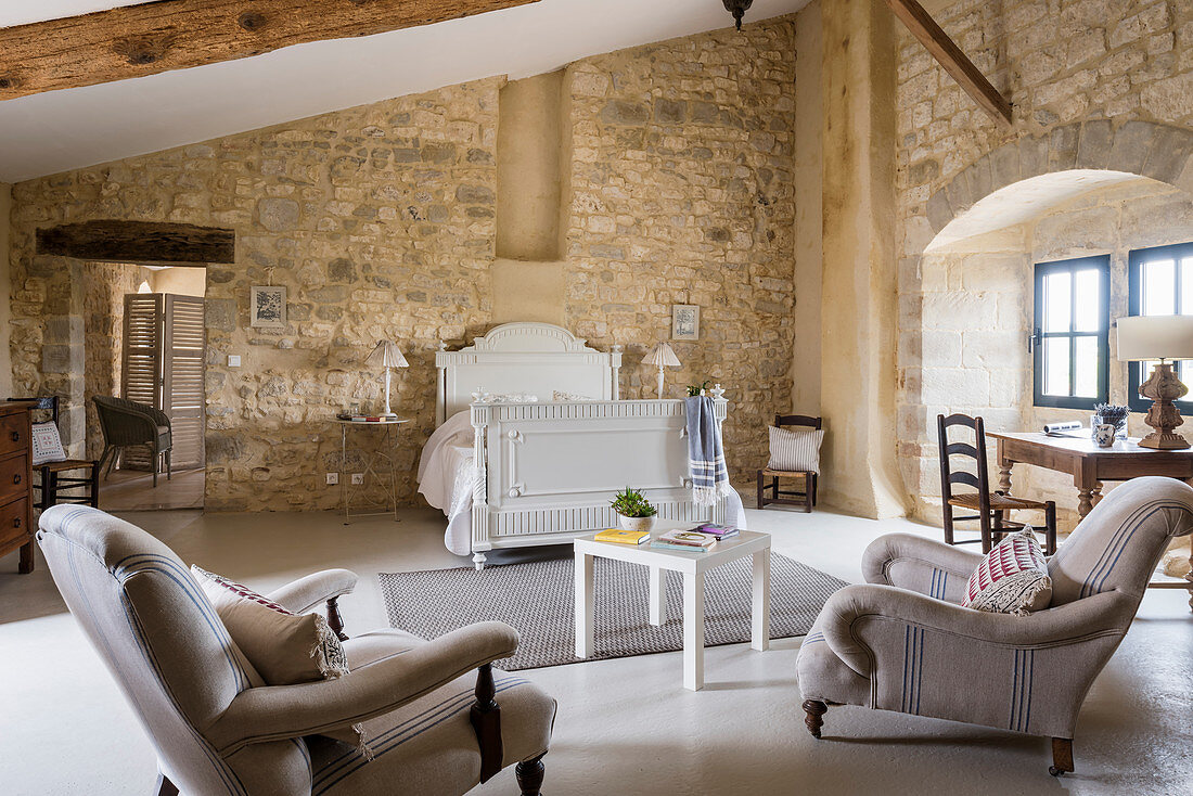 Spacious attic bedroom with upholstered furniture and stone walls
