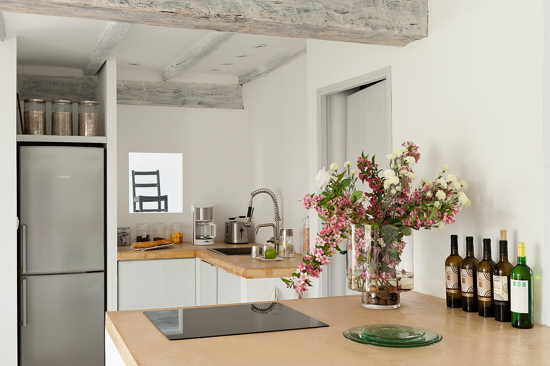 Sandfarbene Betonarbeitsfläche in der Küche mit Blumenvase, im Hintergrund Kühlschrank
