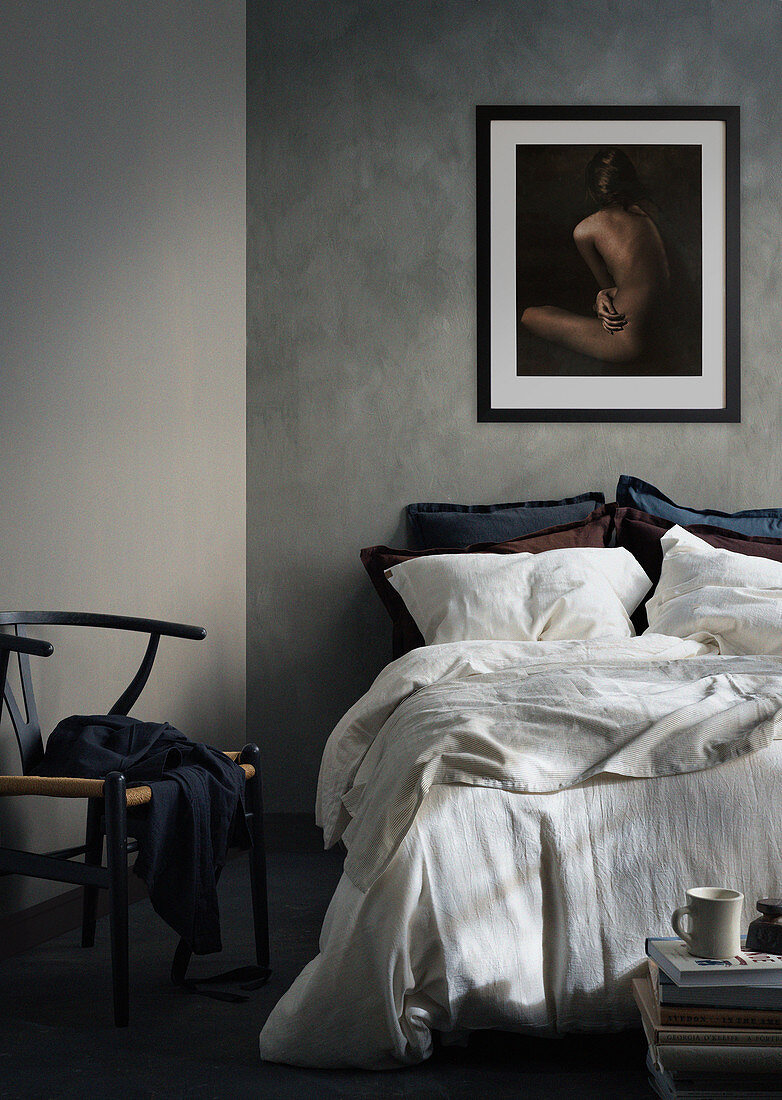 Doppelbett, darüber Aktfoto und Klassikerstuhl im Schlafzimmer mit grauen Wänden