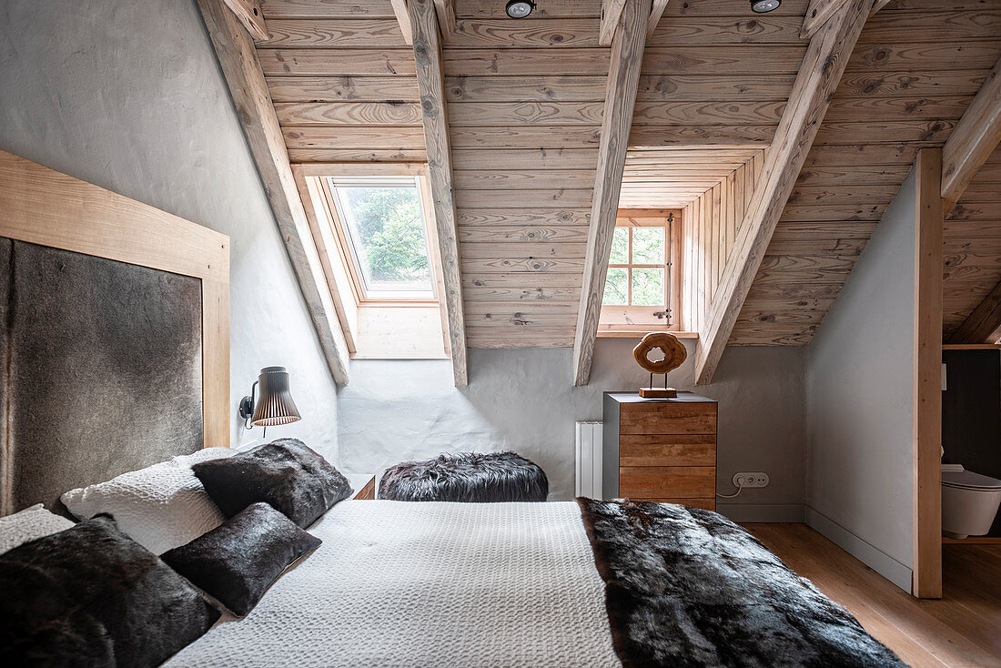 Luxurious double bed in bedroom with wooden ceiling and skylight