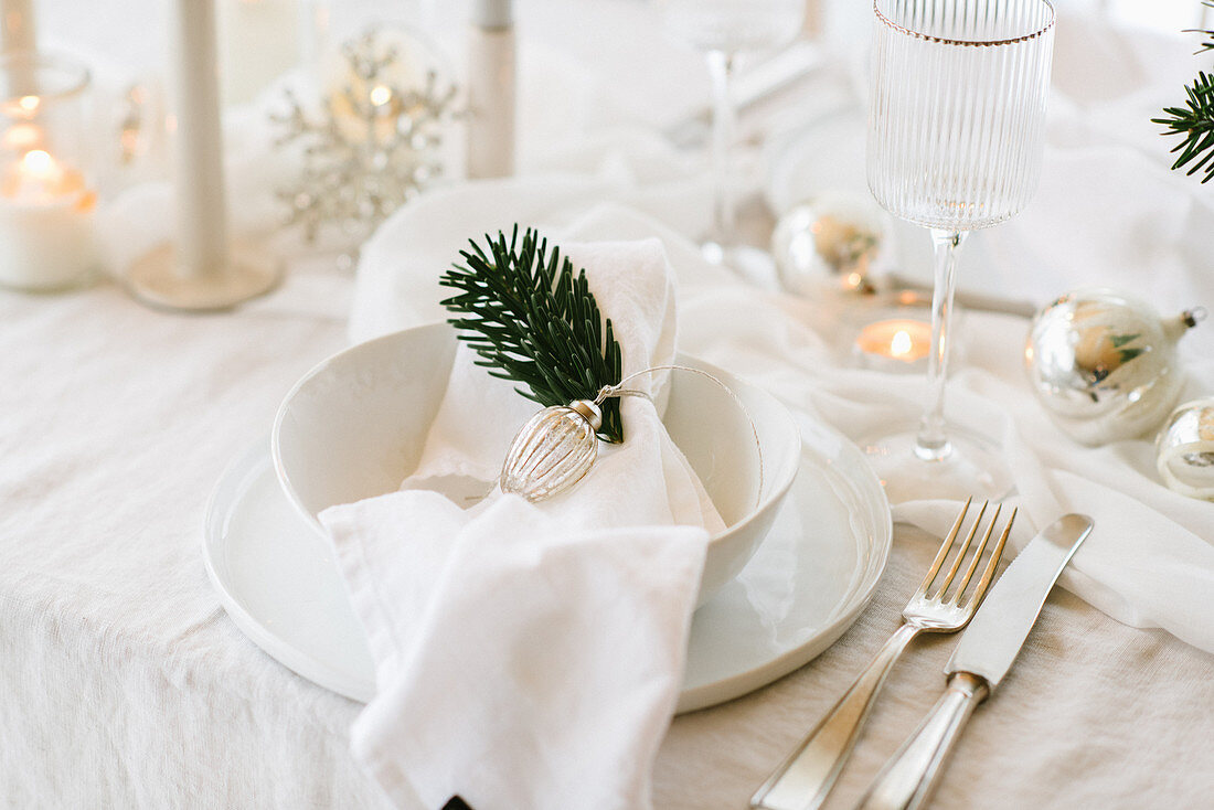 White Christmas place setting decorated with sprig of fir