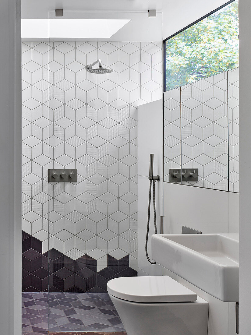 Modernes weiß-graues Badezimmer mit geometrischen Fliesen und Fensterband über Spiegel