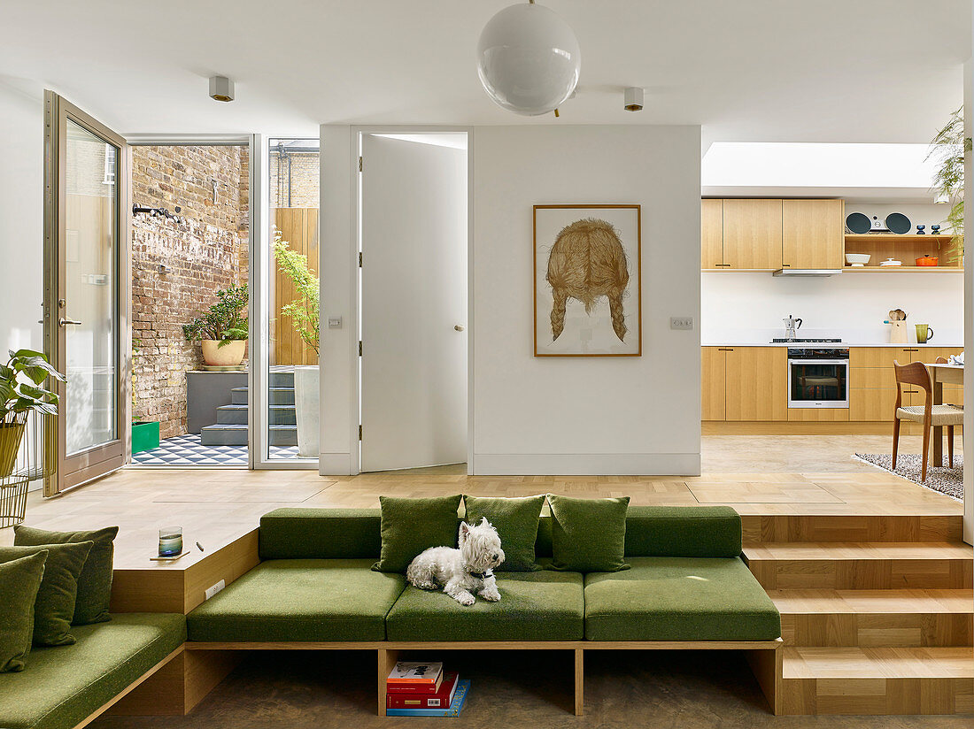Einbausofa mit grünen Sitzauflagen neben Treppe zum Küchenbereich auf Splitlevel-Ebene