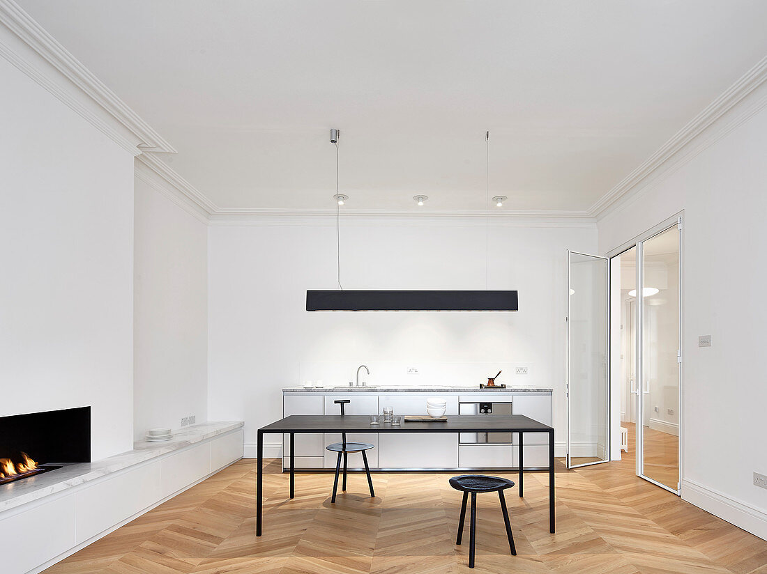 Kitchen counter, table and fireplace in open-plan interior with modern minimalist furnishings