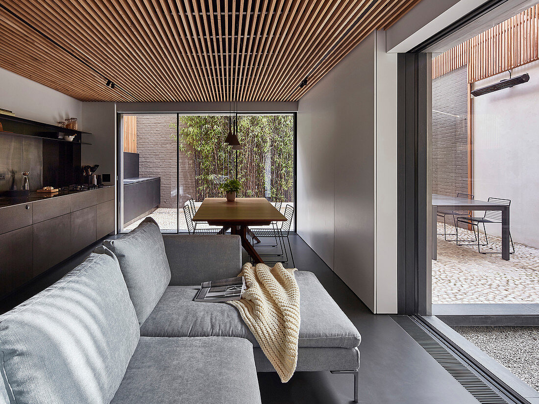 Sofa, dining table and kitchen counter in open-plan interior with view of courtyard