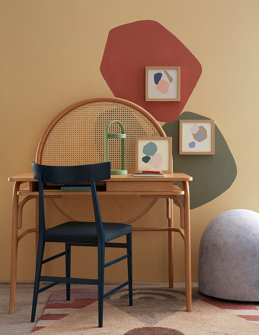 Blauer Stuhl und Schreibtisch vor bunten Farbfeldern an der Wand