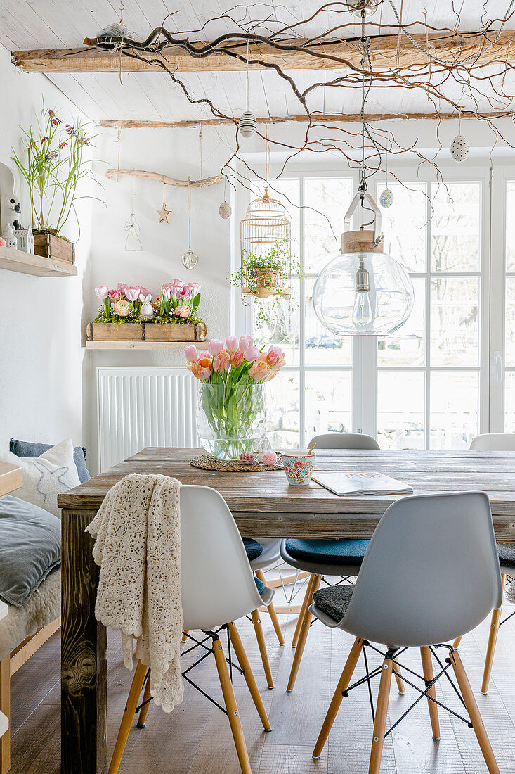 Grey shell chairs around wooden table in dining room with spring decorations
