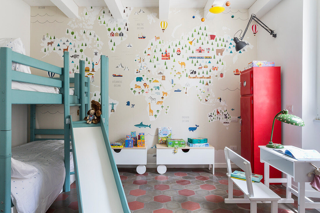 Bunk beds with slide and wallpaper with map of the world in children's bedroom