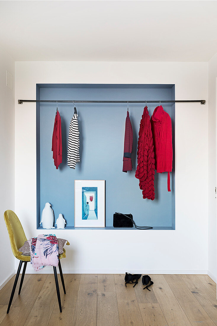 Chair and clothes rail in front of pale blue niche
