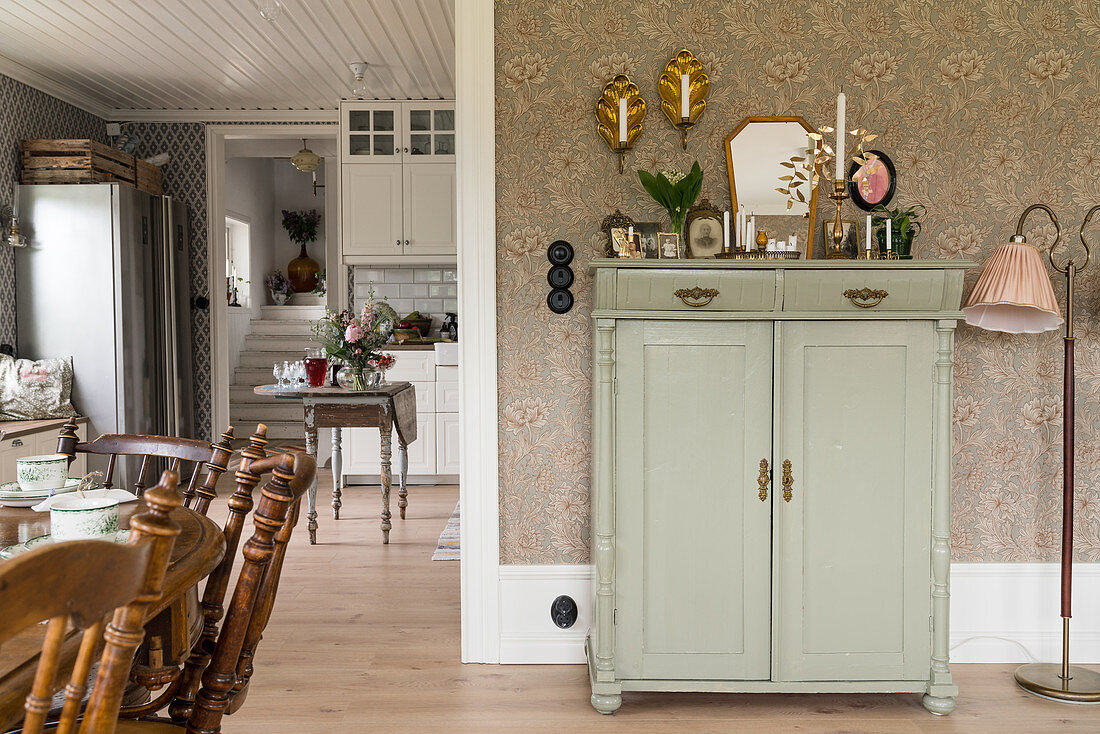 Antique cabinet against patterned wallpaper in dining room