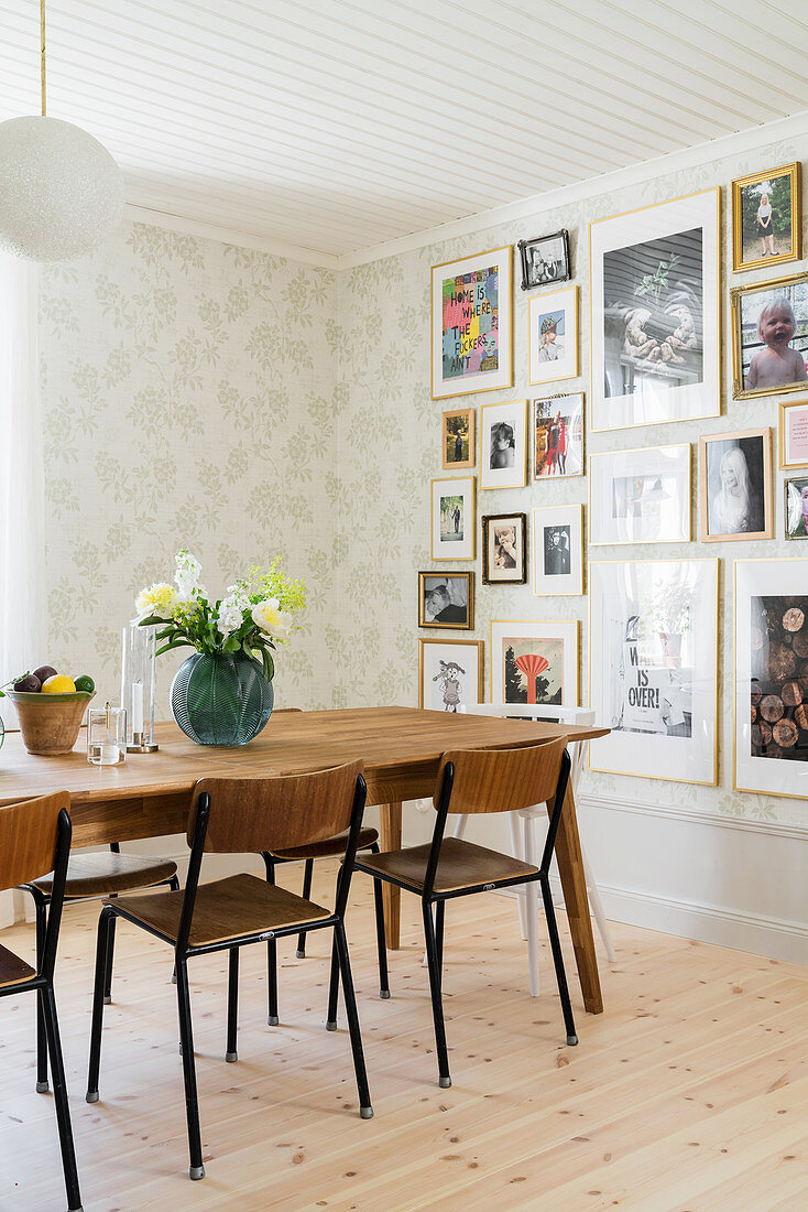Gallery of pictures on wall of dining room with patterned wallpaper