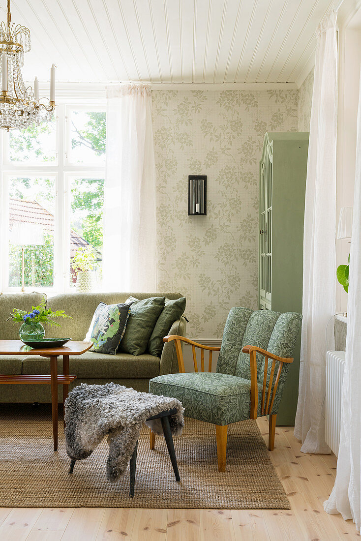 Green upholstered furniture and patterned wallpaper in living room
