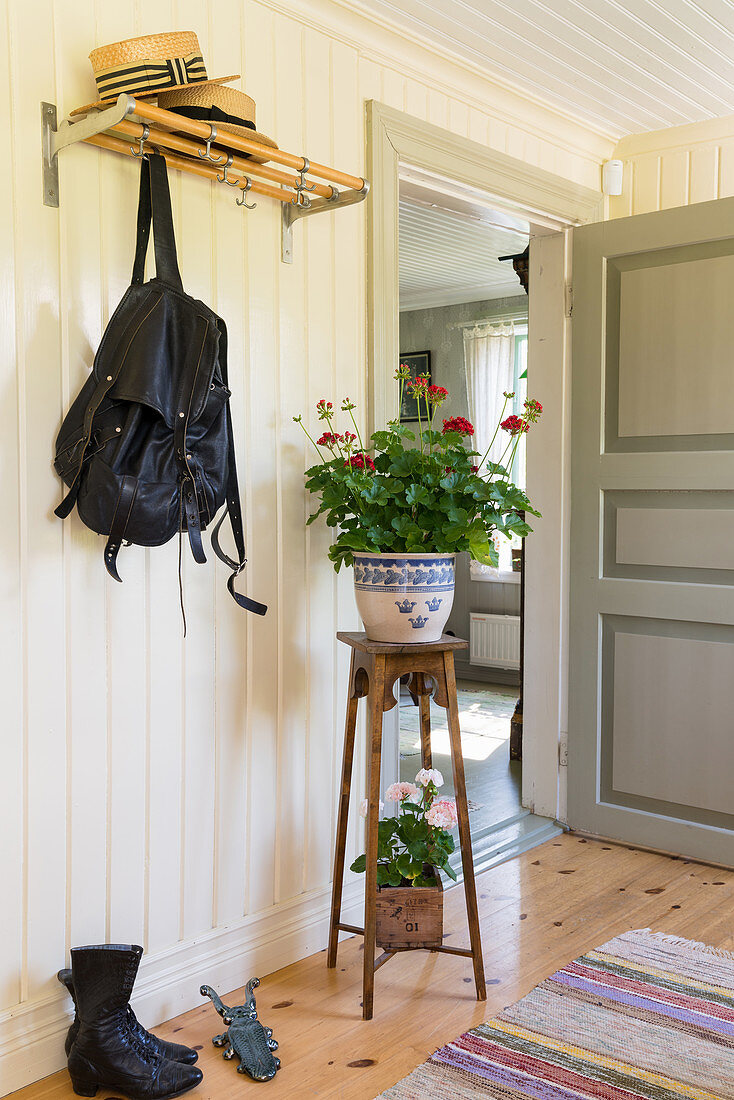 Plant stand in hallway with white-painted, wood-clad walls