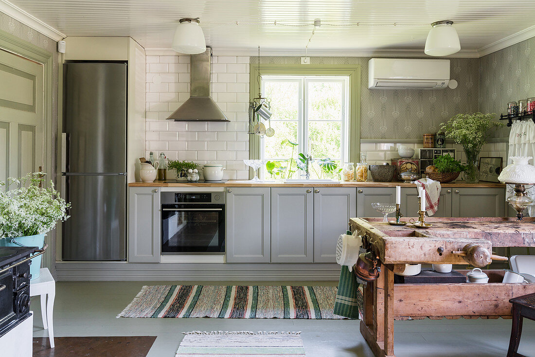 Grey cabinets in country-house kitchen with antique table in foreground