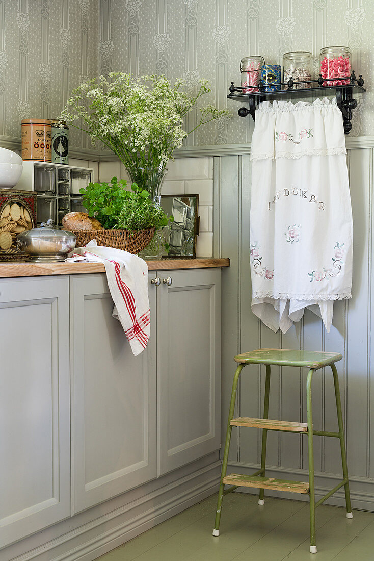 Grey cabinets, step stool and shelf in country-house kitchen