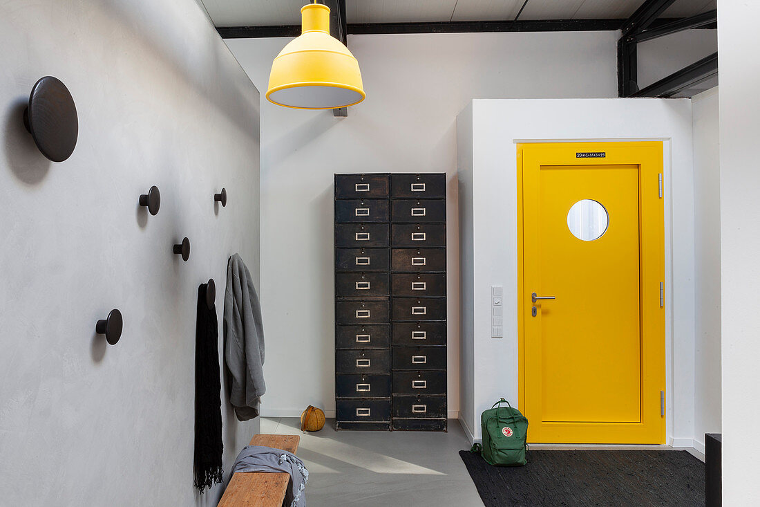 Blick auf Schubladenschrank im Industriedesign und gelbe Tür in Loft-Wohnung