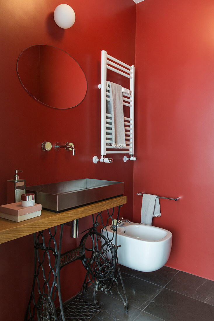 Sewing machine table used as washstand in bathroom with red walls