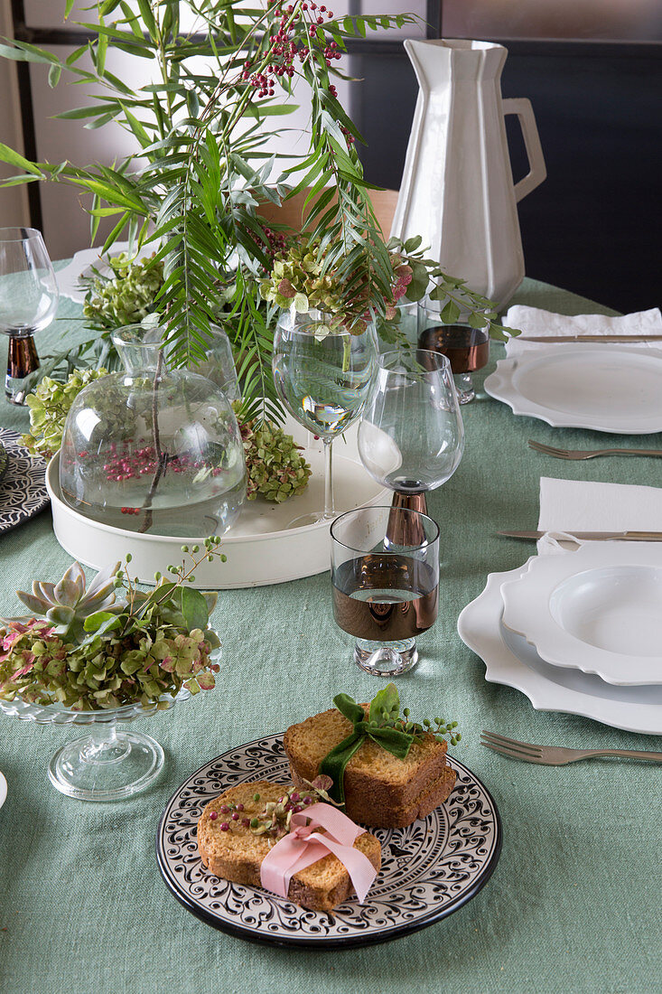 Brote mit Stoffbändern auf gedecktem Tisch mit Blumendeko