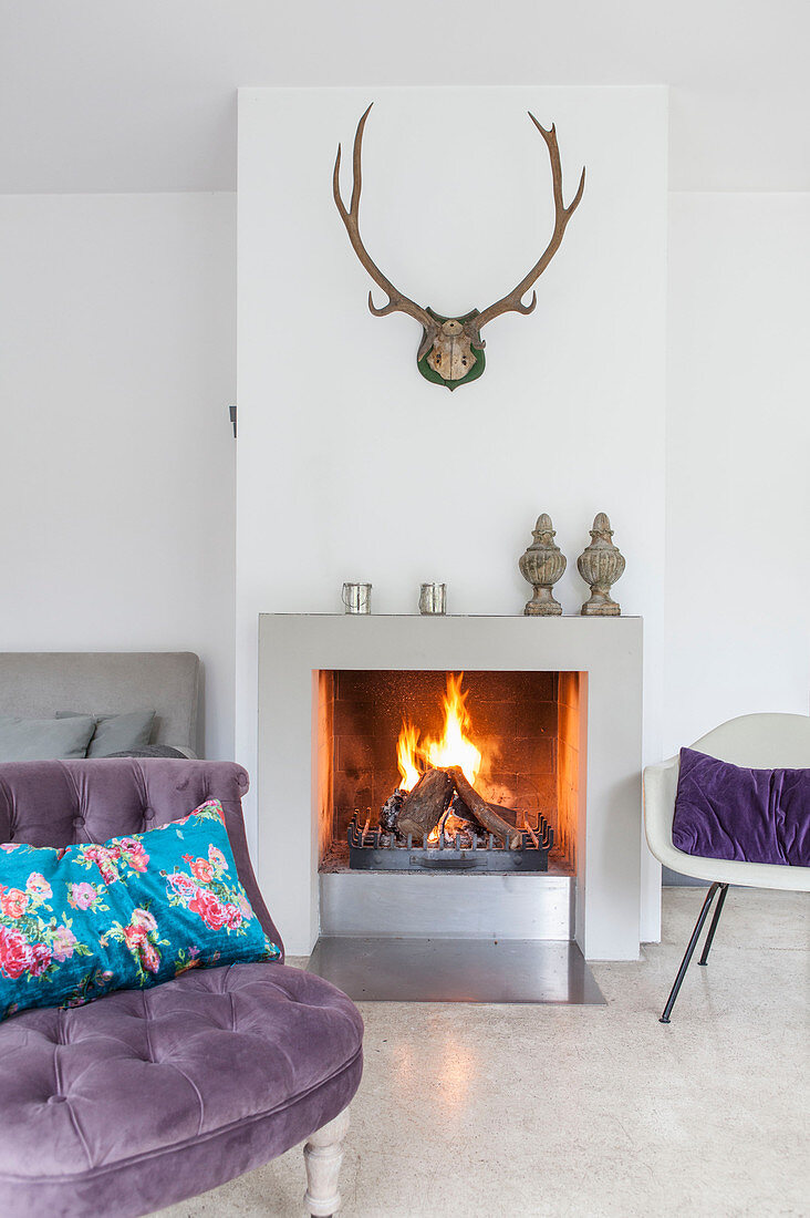 Antlers above fireplace in living room with purple easy chair in foreground