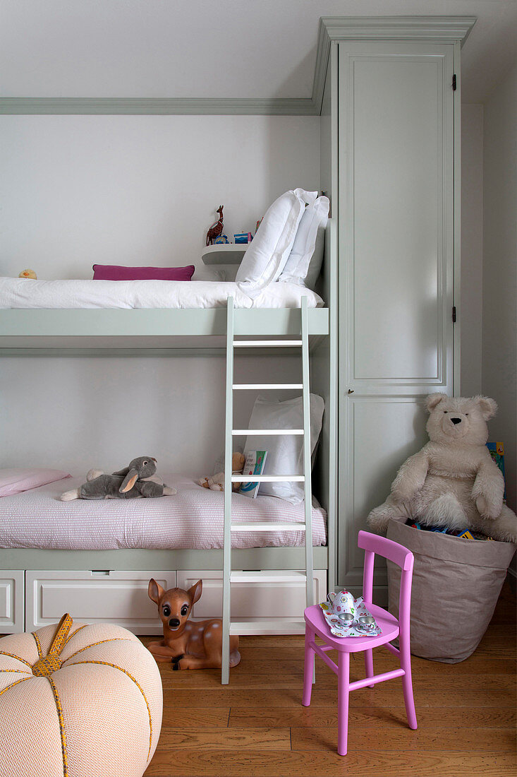 Pink chair next to bunk beds in classic children's bedroom
