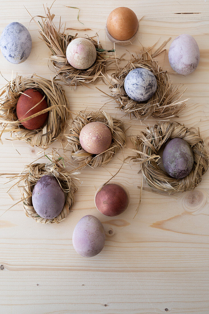 Easter eggs coloured using natural dyes in nests of straw