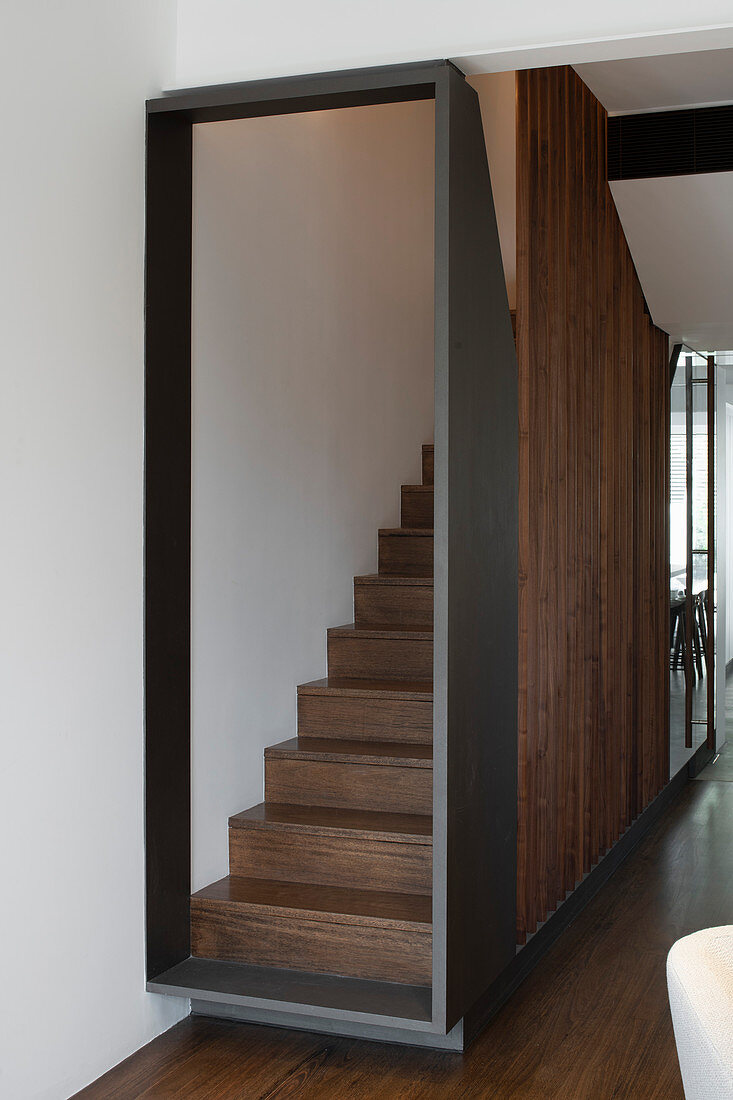 Grau gerahmter Aufgang zur Treppe mit dunklen Holzstufen