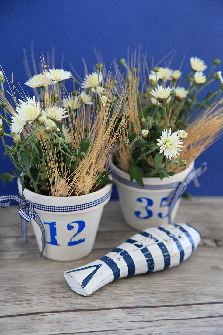 Arrangement of white asters and ears of barley in blue-and-white pots and wooden fish