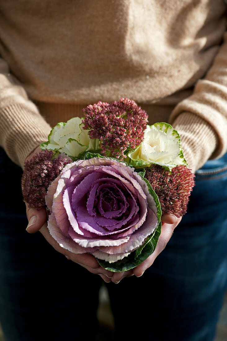Woman holding bouquet of ornamental cabbages and sedum
