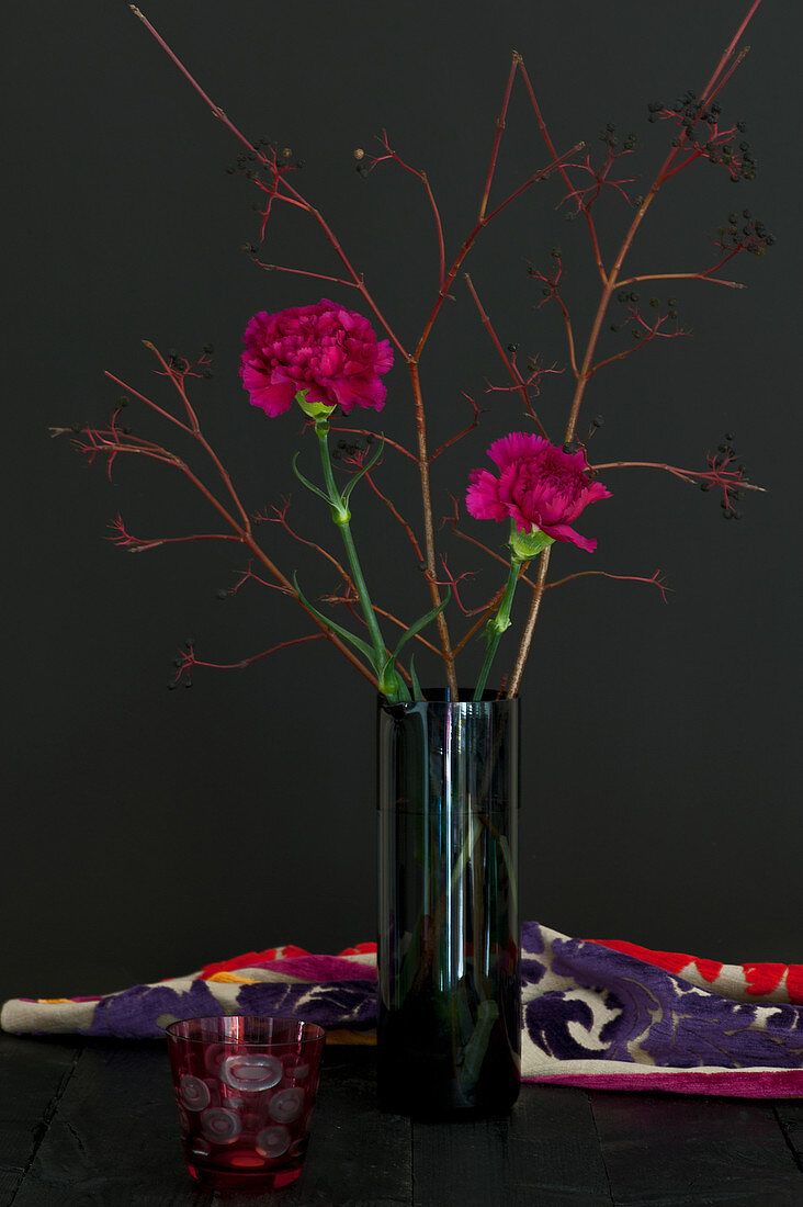 Modern arrangement of carnations and twigs in glass vase