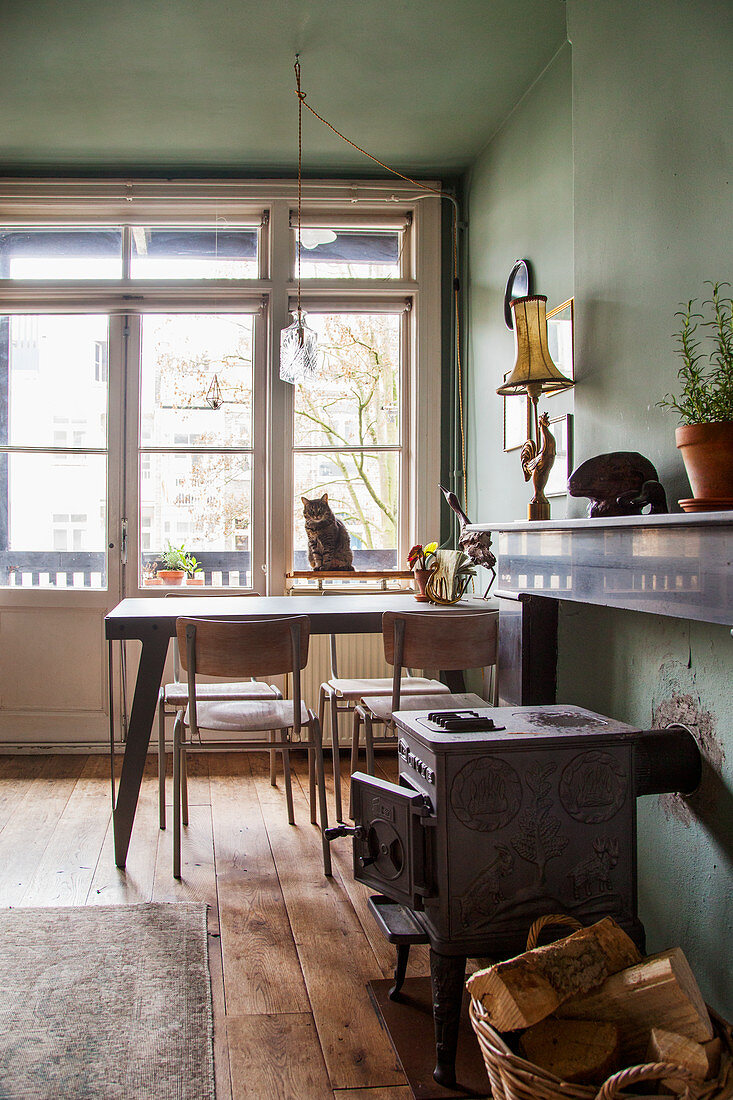 Holzofen und Essbereich vor Fenster mit Katze