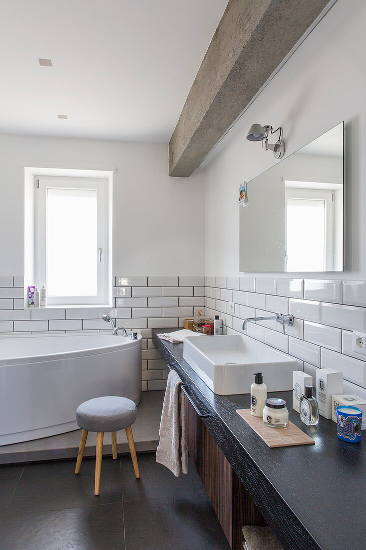 Washstand and free-standing bathtub in bathroom with subway tiles