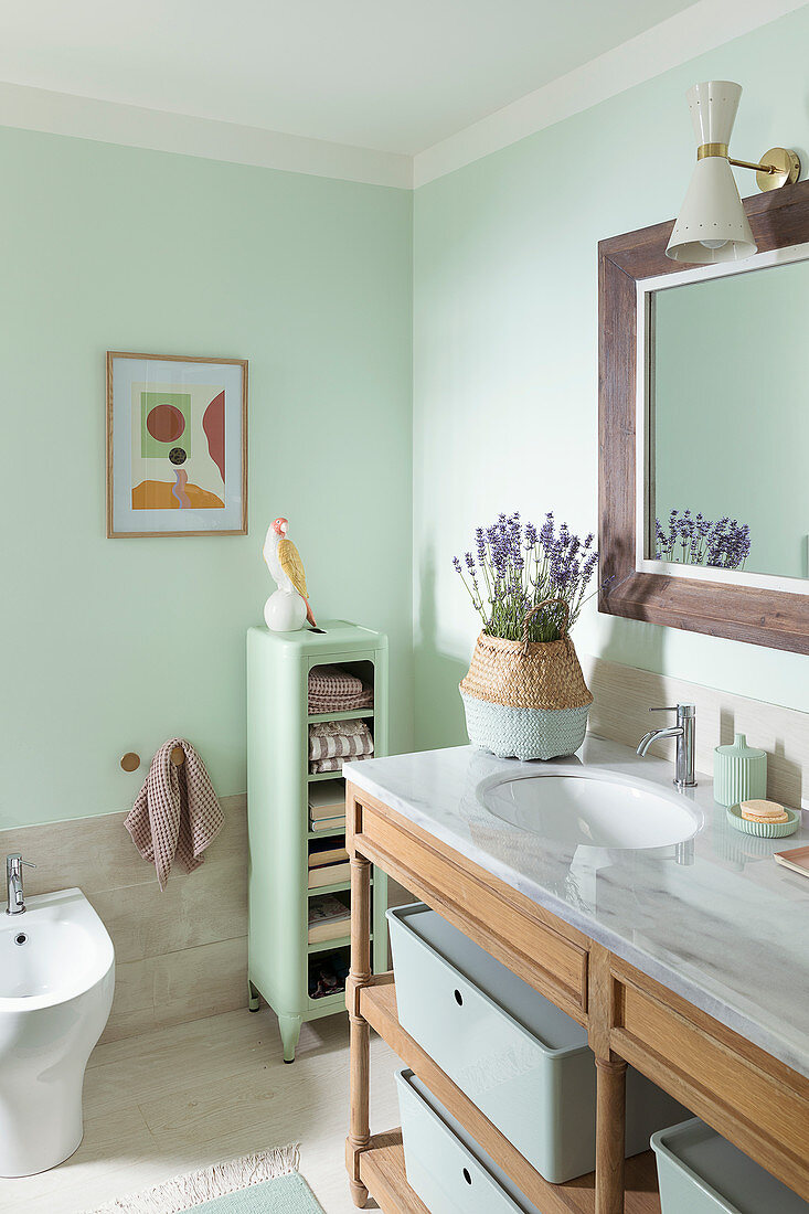 Waschtisch mit Marmorplatte und Regalschrank im Badezimmer mit grünen Wänden