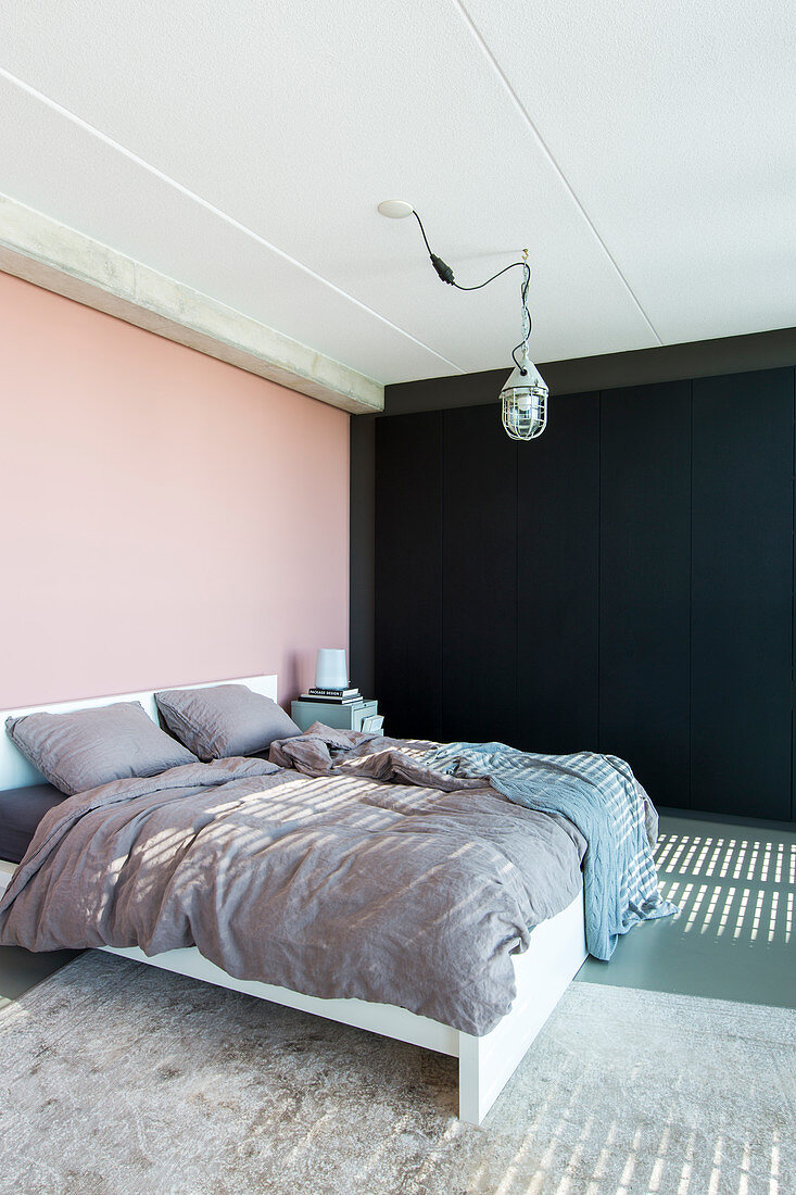 Double bed in bedroom with pink and black walls