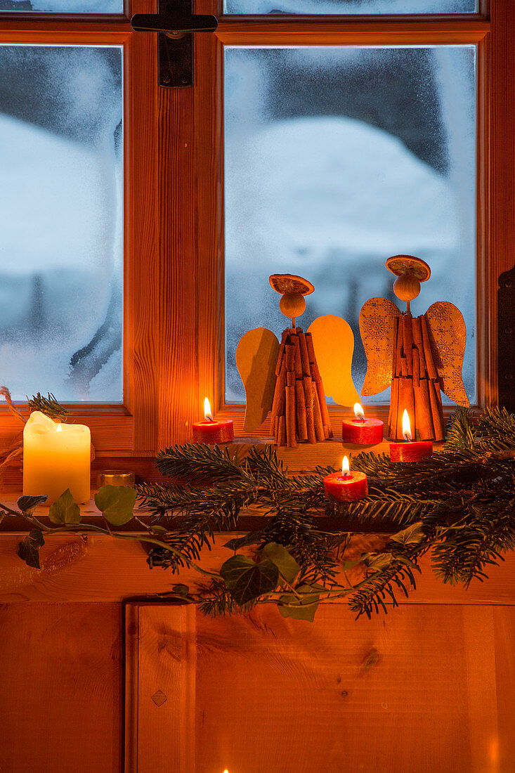 Engel aus Zimtstangen und Kerzendeko am ländlichen Fenster