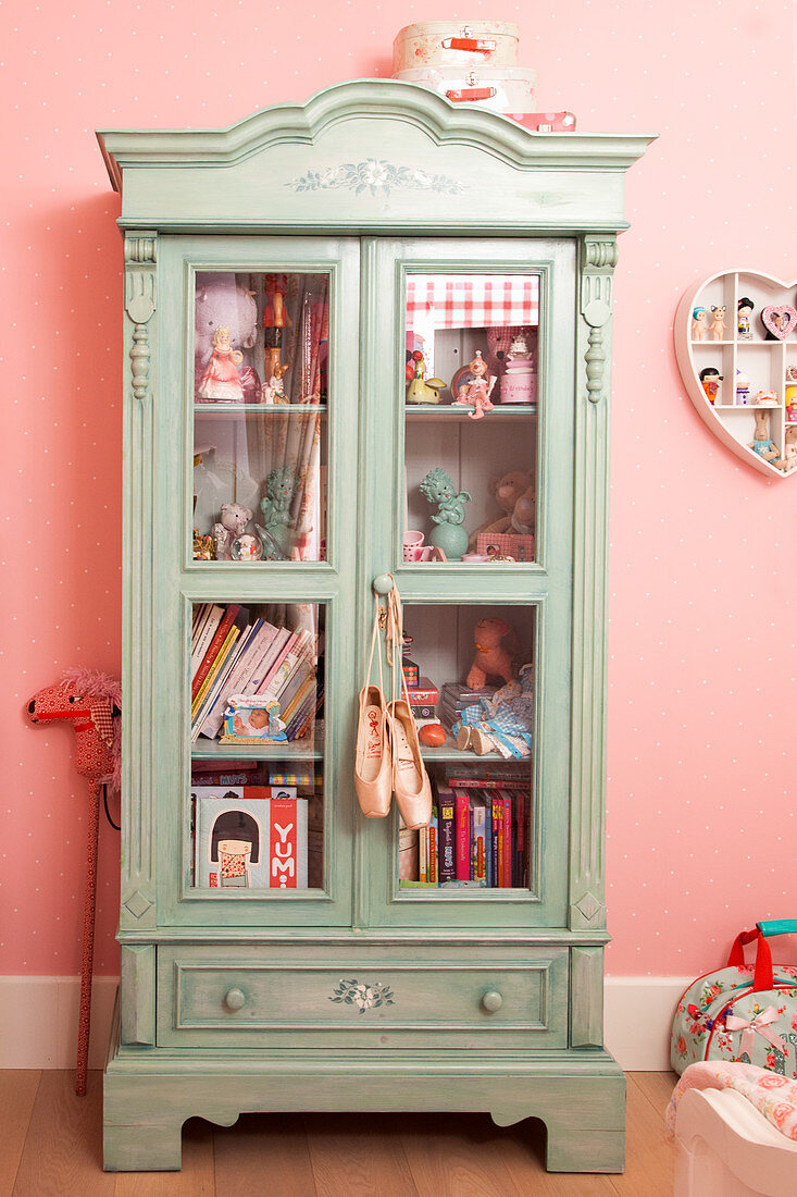Antique glass-fronted cabinet in girl's bedroom