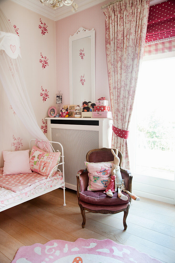 Bed with bed crown and armchair in girl's bedroom