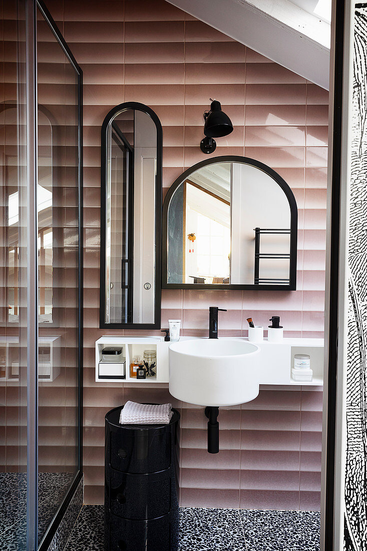 A view into a bathroom with a hand basin and mirrors