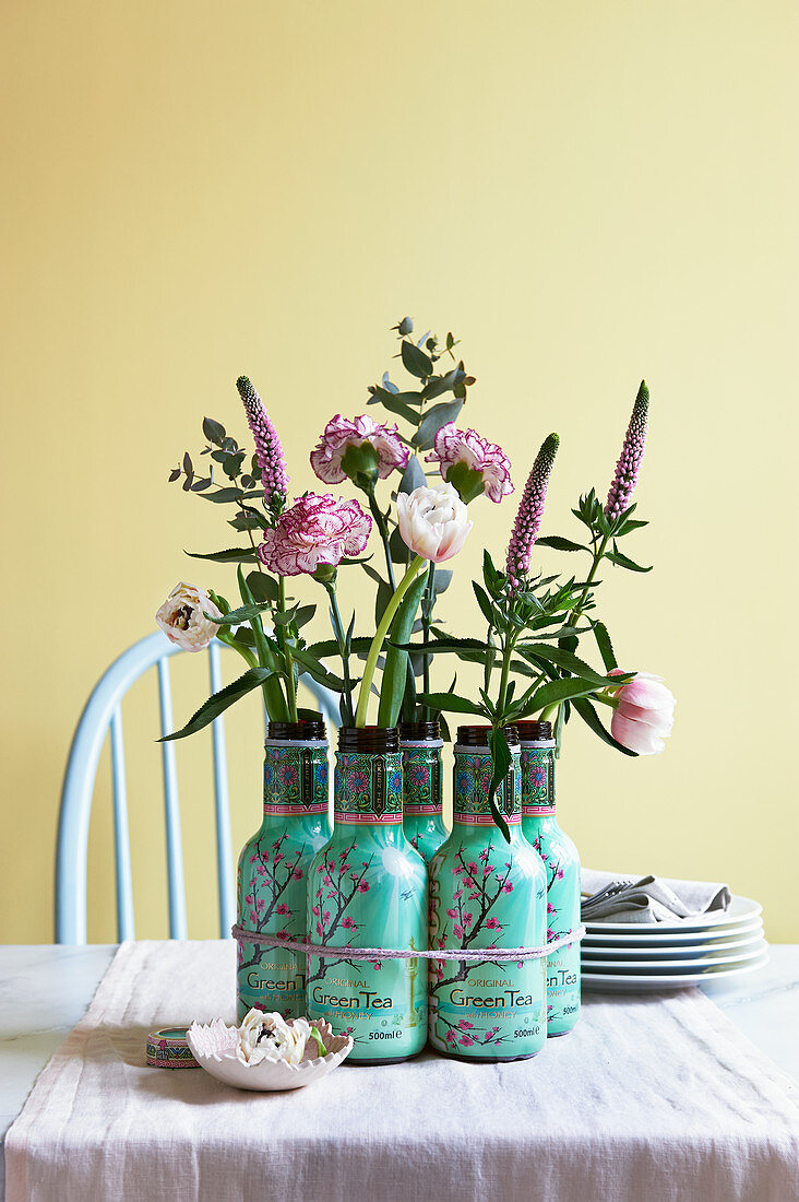 Carnations, veronica and eucalyptus in empty bottles used as vases