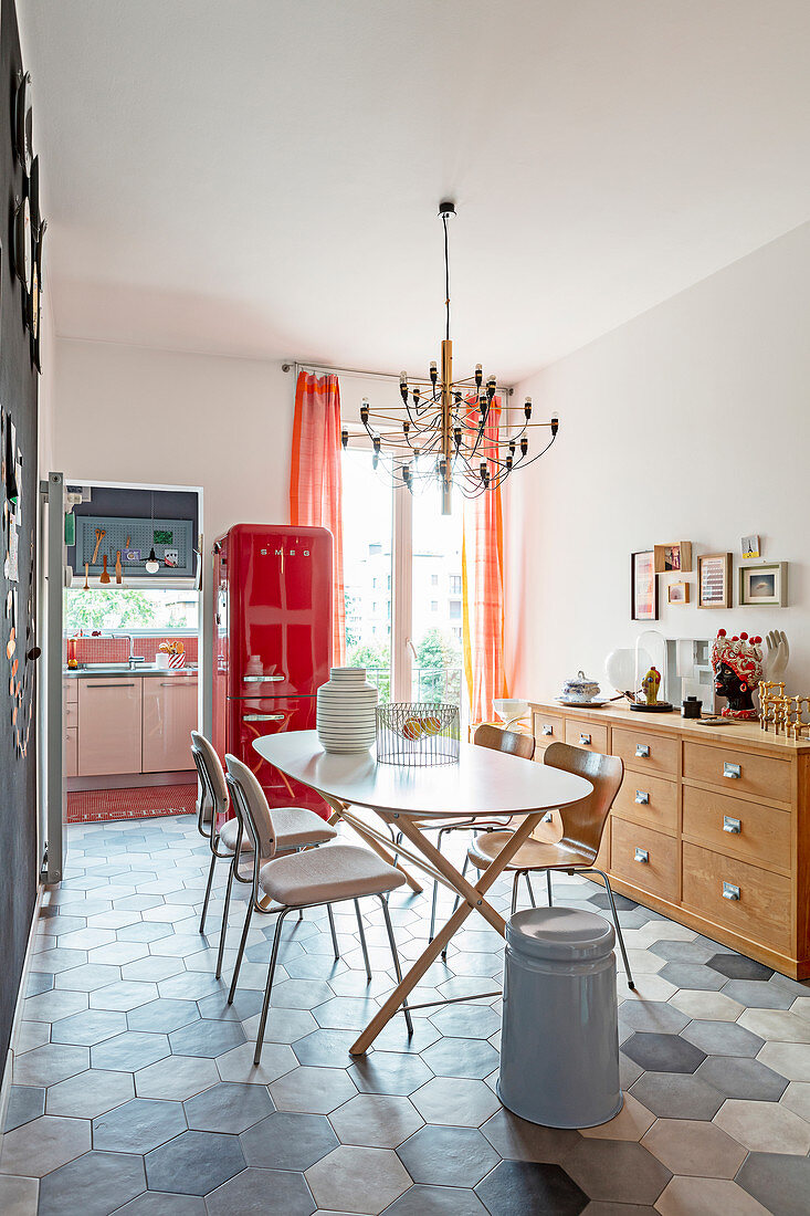 Ovaler Tisch mit Stühlen und roter Kühlschrank im Esszimmer
